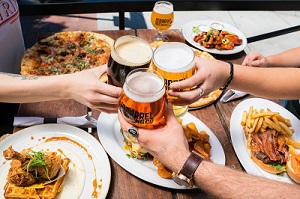 Three glasses clinked together with food on plates under them
